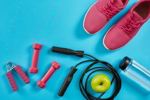 Flat lay of female sport equipments, jump rope, bottle of water and pink sneakers on blue background photo