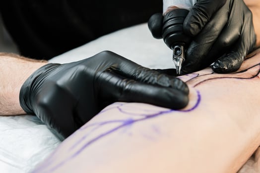 Professional tattoo artist makes a tattoo on the male leg photo