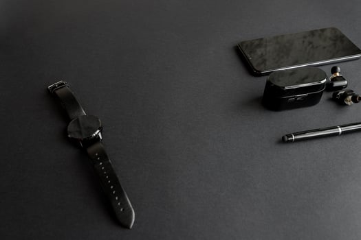 black pen, black smart watch, smartphone, wireless headphones on dark background photo