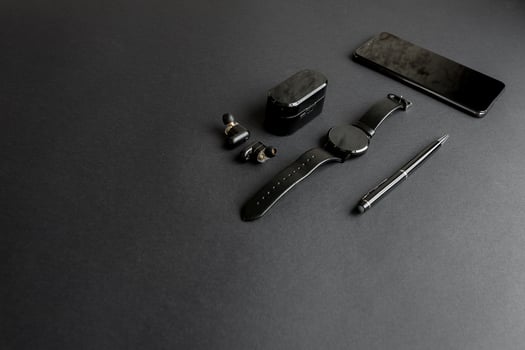 black pen, black smart watch, smartphone, wireless headphones on dark background photo
