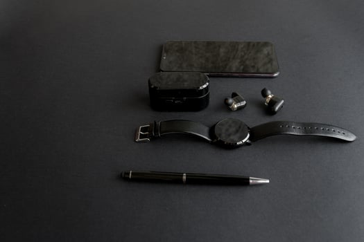 black pen, black smart watch, smartphone, wireless headphones on dark background photo