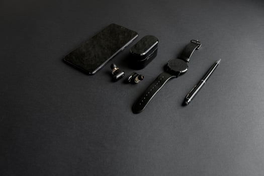 black pen, black smart watch, smartphone, wireless headphones on dark background photo