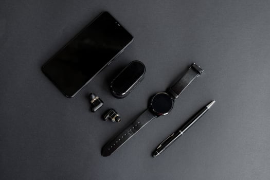 black pen, black smart watch, smartphone, wireless headphones on dark background photo