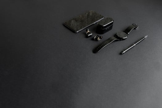 black pen, black smart watch, smartphone, wireless headphones on dark background photo