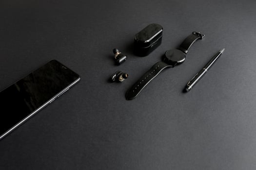 black pen, black smart watch, smartphone, wireless headphones on dark background photo