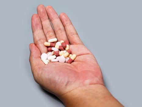 hand pouring capsules from medication take pharmaceutical healthcare treatment concept, close up view Colorful pills and medicines in the hand photo