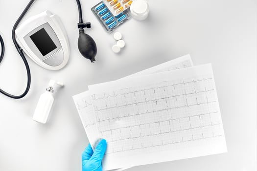 Top view of doctor's hand with result of the survey, digital blood pressure monitor on white table photo