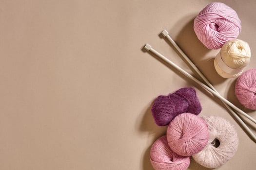 A group of colored balls of yarn and knitting needles on a beige background photo