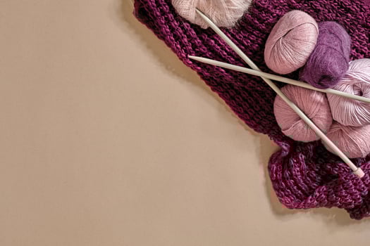 A group of colored balls of yarn and knitting needles on a beige background photo