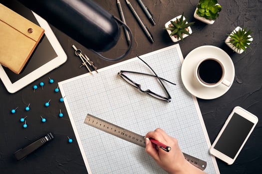 Office desk background hand with pen writing construction project ideas concept. With tablet, drawing equipment and a cup of coffee. View from above photo