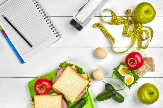 Healthy lunch in office at workplace or home. Whole-grain sandwich with ham and fresh vegetables and bottle of water. Top view, flat lay on wood photo