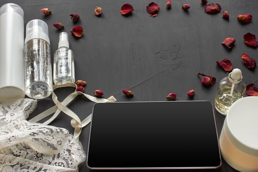Composition with skin care cosmetic products without label and white lingerie on a black desktop background. photo