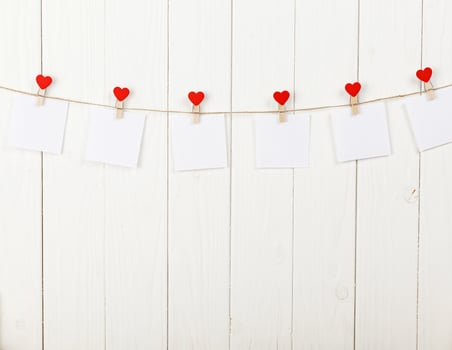 white pieces of paper on clothespins with a heart on a wooden background photo