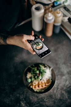 Cropped view of man taking photo of salad with smartphone in cafe