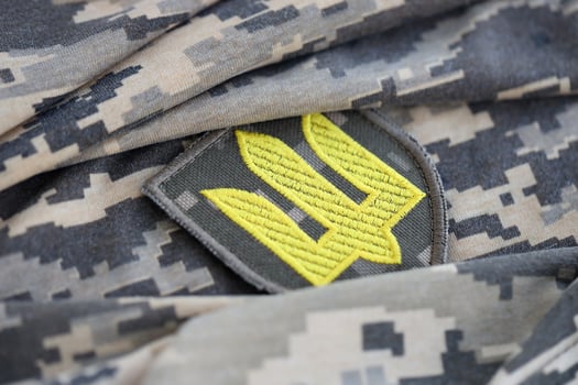 Symbol of Ukrainian army on the camouflage uniform of a Ukrainian soldier. The concept of war in Ukraine, patriotism and protecting your country from occupiers photo