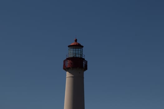 This is the top image of Capy May point lighthouse. The red metal top stands out against the white brick of the tower. photo