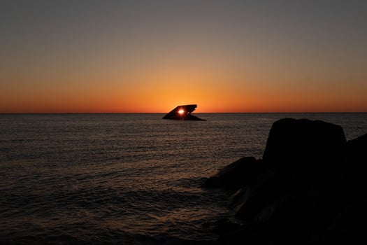 The sunken ship of Cape May New Jersey during sunset. The sun lining up perfectly with hull to look like a glowing eye. The sky has beautiful colors of orange almost like it is on fire. photo