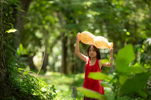 Little asian girl in red dress holding fishing equipment in the forest, Rural Thailand living life concept photo