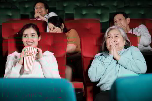 Various people in theater. Asian senior woman and many audiences are scared of watching thriller and horror cinema, frightened together on movie stage, and entertainment lifestyle with film show. photo