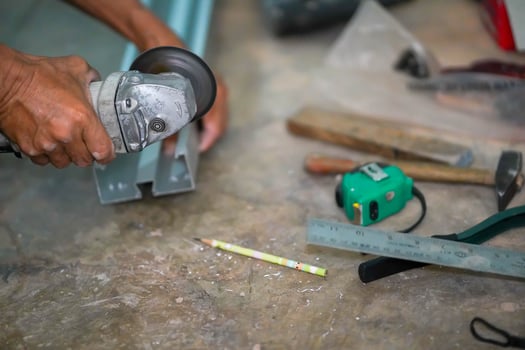 Closeup hands of the master saw the metal holding electric angle grinder working cutting aluminum lumber at construction site. photo