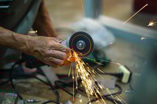 Closeup hands of the master saw the metal holding electric angle grinder working with sparks in metalworking at construction site. photo