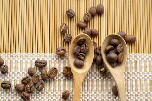 Roasted coffee beans in wooden spoon and spread on woven bamboo placemat. It is a medium roast with medium intensity coffee flavor. Slightly sweet and sour, suitable for both hot and cold coffee. photo