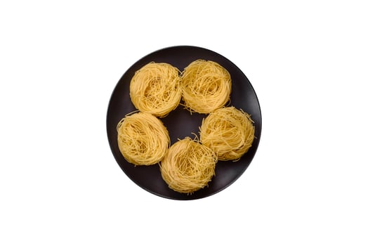 Raw capellini pasta or noodles with salt and spices photo