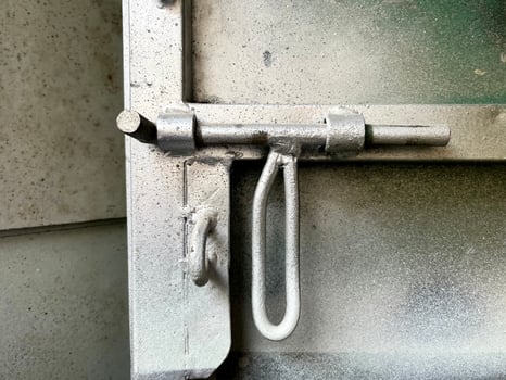 Metal iron sliding lock with long handle for locking gate door. Industrial door interior close up object isolated on grungy and textured spray painted metal door. photo