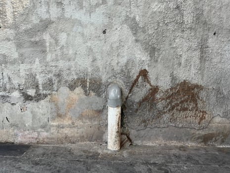 Unclean concrete wall outdoor with grungy textured stain isolated on horizontal ratio and water pipe going down to the ground object. photo