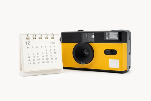 Simple desk calendar for December 2023 and film camera isolated on white background. Calendar and holiday concept with copy space. photo