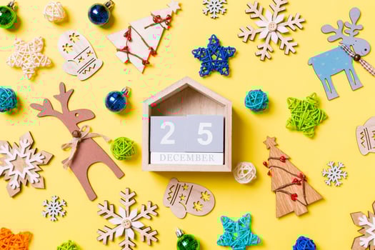 Top view of wooden calendar on yellow background with New Year toys and decorations. The twenty fifth of December. Christmas time concept photo