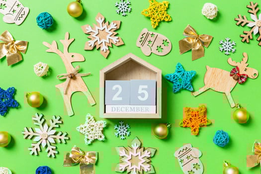 Top view of wooden calendar on green background with New Year toys and decorations. The twenty fifth of December. Christmas time concept photo