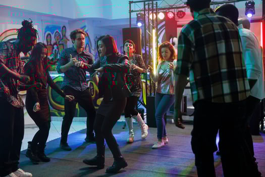People partying in nightclub while having fun and dancing on dancefloor with spotlights together. Young men and women crowd attending discotheque and music concert in club photo