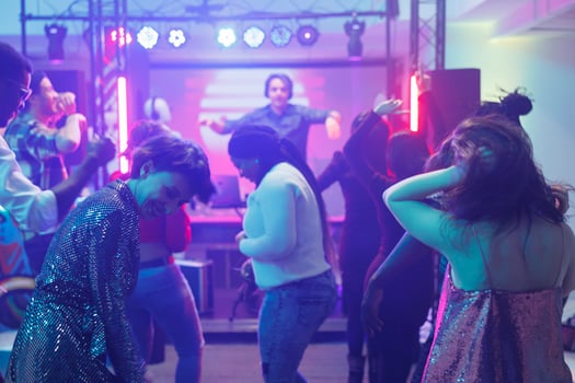 Young people clubbing and partying while dancing in nightclub at electronic music performance. Diverse crowd making moves on dancefloor while having fun and enjoying nightlife photo