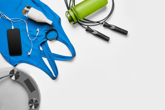 Sport, fitness, healthy lifestyle, cardio training and objects concept - close up of female sports clothing, skipping rope and bottle set photo