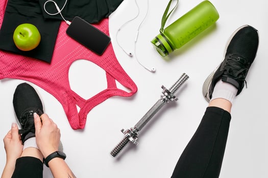 Young woman in sporting leggings laces sneakers, preparing for training. Accessories for sports on white background flat lay top view. photo