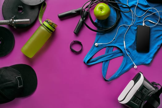 Health fitness background. Sneakers, dumbbell, power grip, green apple, water bottle, blue shirt, phone and earphone on dark background. photo