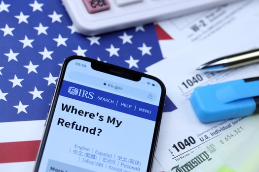 KHARKOV, UKRAINE - MARCH 5, 2021 Official IRS website on iPhone 12 pro screen with 1040 and w-2 paper tax forms on US flag photo