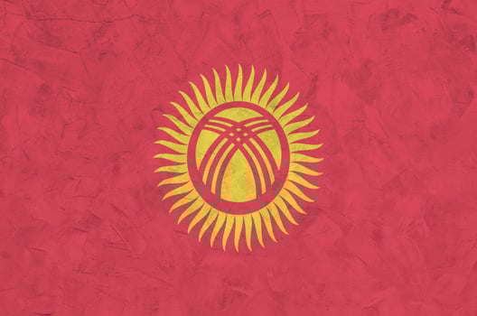 Kyrgyzstan flag depicted in bright paint colors on old relief plastering wall. Textured banner on rough background photo