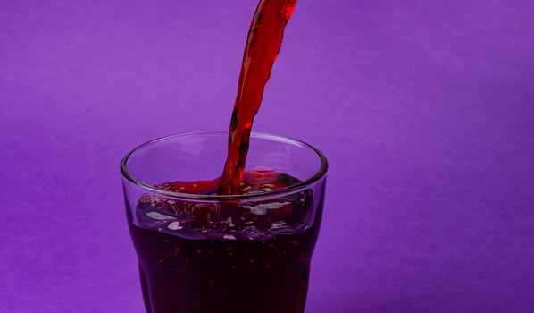 Cherry juice pouring into glass, isolated on purple background, with copy space photo