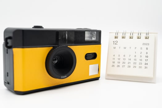 Simple desk calendar for December 2023 and film camera isolated on white background. Calendar and holiday concept with copy space. photo