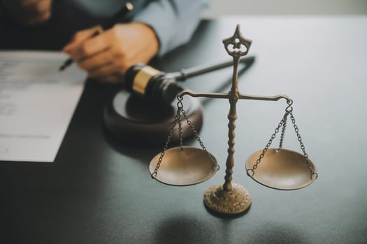 Business and lawyers discussing contract papers with brass scale on desk in office. Law, legal services, advice, justice and law concept picture with film grain effect photo