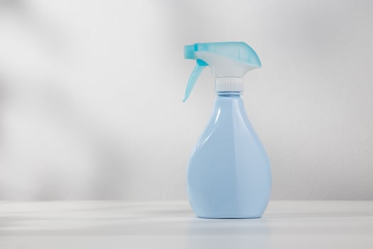 Blue spray bottle on white wooden table. photo