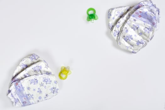 Babies goods diaper, soother or nipple on white background with copy space. Top view or flat lay. photo