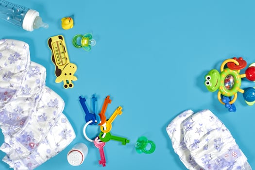 Babies goods cloth diaper, baby powder, nibbler, cream, teether, soother, baby toy on blue background. Copy space. Top view. photo
