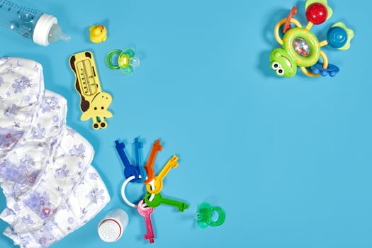 Babies goods cloth diaper, baby powder, nibbler, cream, teether, soother, baby toy on blue background. Copy space. Top view. photo