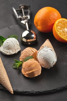 Close-up shot of a creamy and orange ice cream served on a dark slate, black background. photo