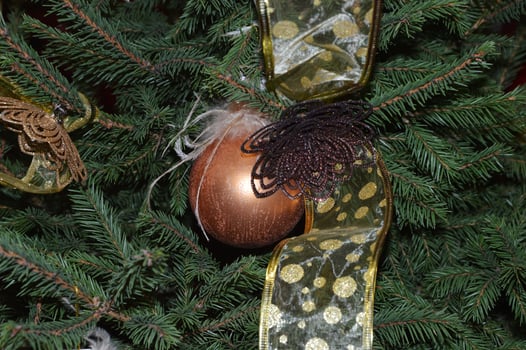 New Year's decoration in the shape of a golden ball with a ribbon on the Christmas tree. Festive background. photo