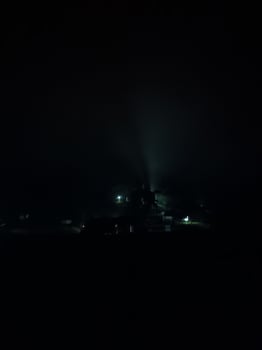 fir trees on meadow between hillsides with conifer forest in fog under the blue sky at night. spooky countryside scenery in full moon light photo