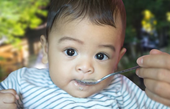 Eating from spoon of six month asian baby photo